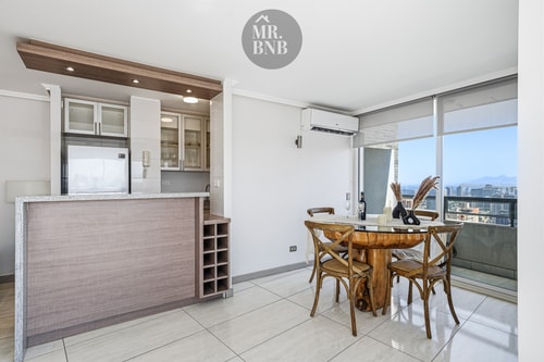 Comedor junto a barra de cocina, mesa redonda con cuatro sillas de mimbre
